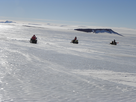Snowmobile sweeps across the vast blue ice at Davis-Ward 