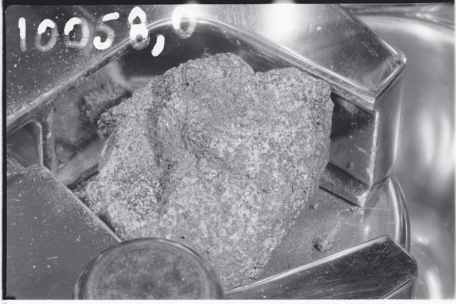 Black and white photograph of Apollo 11 Sample(s) 10058; Processing photograph displaying chipping.