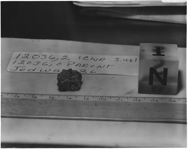 Black and white photograph of Apollo 12 Sample(S) 12036,2; Processing photograph displaying a chip sample with an orientation of T,N.
