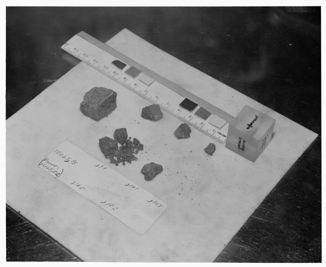 Black and white photograph of Apollo 12 Sample(S) 12065,98-103; Processing photograph displaying a group post chip sample with an orientation of T,N,W.