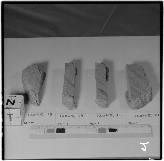 Black and white photograph of Apollo 12 Sample(S) 12065,18-21; Processing photograph displaying a slab reconstruction sample with an orientation of N,T.