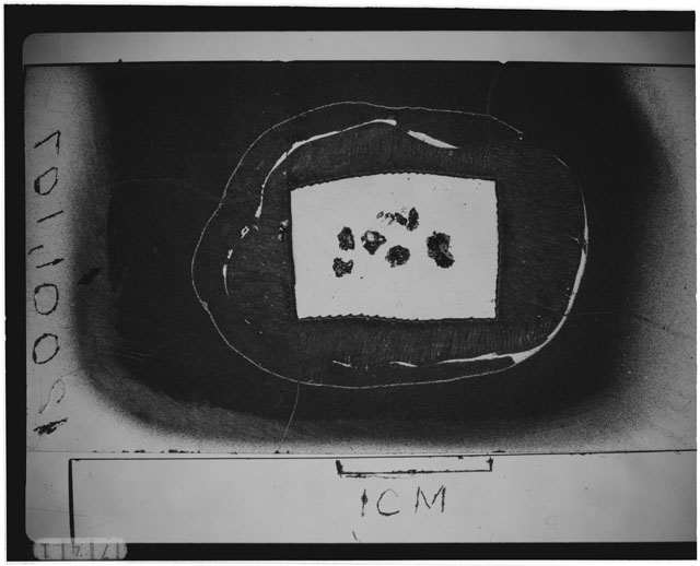 Black and white photograph of Apollo 12 sample 12001,104; Thin Section photograph displaying grain mount.