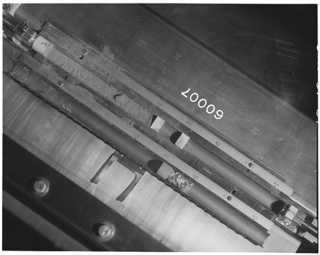 Black and white photograph of Apollo 16 Core Sample 60007; Processing photograph displaying an overview of the Core Tube with drill stem.