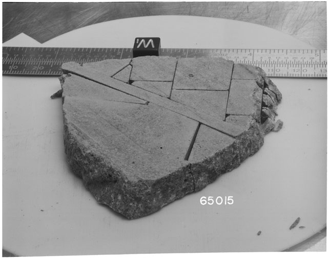Black and white photograph of Apollo 16 Sample(s) 65015; Processing photograph displaying slab reconstruction with an orientation of W.