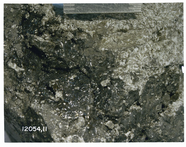 Color photograph of Apollo 12 Sample(S) 12054,11; Processing photograph displaying surface close up.