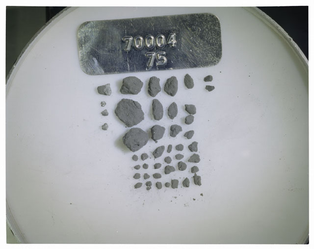 Color photograph of Apollo 17 Sample(s) 70004,75; Processing photograph displaying a group of >1 MM Core Fines found at 183.2-183.7 cm depth from surface.