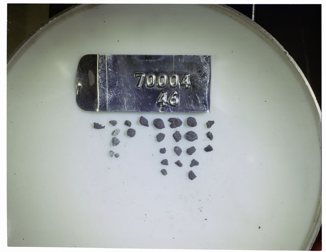 Color photograph of Apollo 17 Sample(s) 70004,46; Processing photograph displaying a group of >1 MM Core Fines found at 178.7-179.2 cm depth from surface.