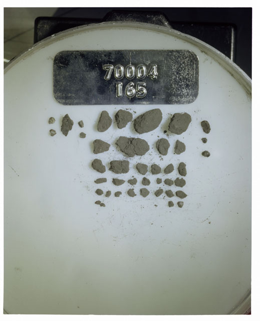 Color photograph of Apollo 17 Sample(s) 70004,165; Processing photograph displaying a group of >1 MM Core Fines found at 197.2-197.7 cm depth from surface.