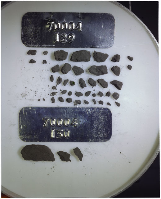 Color photograph of Apollo 17 Sample(s) 70004,129,130; Processing photograph displaying a group of >1 MM Core Fines found at 191.2-191.7 cm depth from surface.