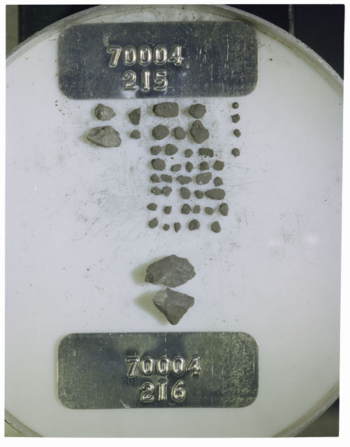 Color photograph of Apollo 17 Sample(s) 70004,215,216; Processing photograph displaying a group of >1 MM Core Fines found at 209.2-209.7 cm depth from surface.