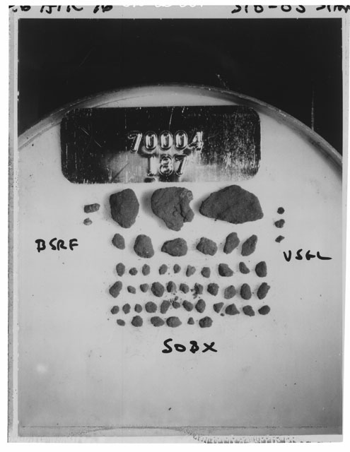 Black and white photograph of Apollo 17 Sample(s) 70004,187; Processing photograph displaying a group of >1 MM Core Fines found at 202.2-202.7 cm depth from surface.