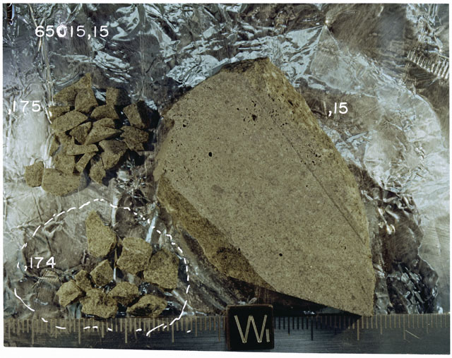 Color photograph of Apollo 16 Sample(s) 65015,15,174,175; Processing photograph displaying sawed surface with chips with an orientation of W.