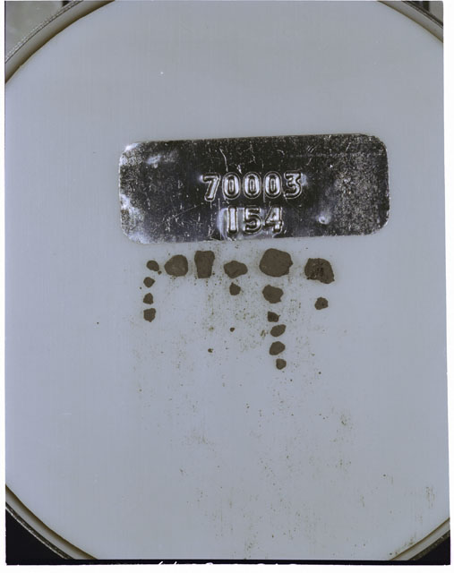 Color photograph of Apollo 17 Sample(s) 70003,154; Processing photograph displaying a group of >1 MM Core Fines found at 242.2-242.7 cm depth from surface.