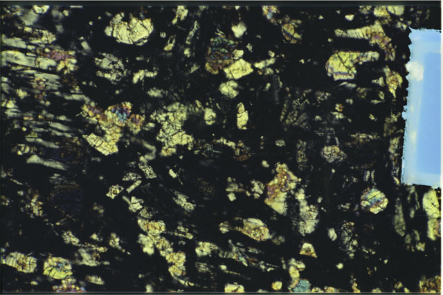 Color photograph of Apollo 16 Sample(s) 61016,220; 1.4 MM Thin Section photograph using cross nichols light.