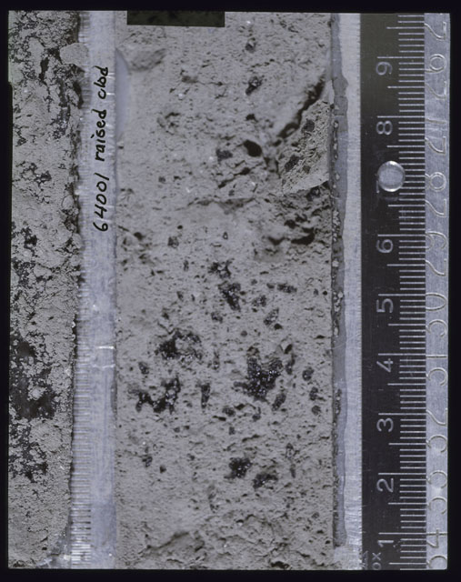 Color photograph of Apollo 16 Core Sample(s) 64001; Processing photograph displaying Core with a raised clod.