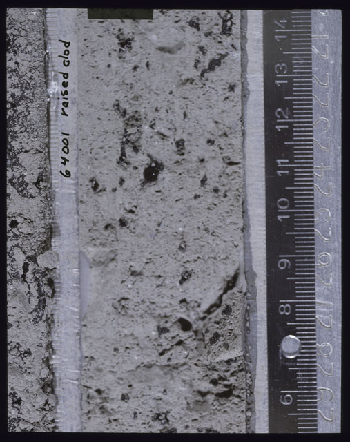 Color photograph of Apollo 16 Core Sample(s) 64001; Processing photograph displaying Core with a raised clod.