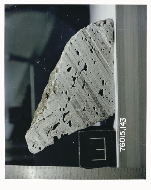 Color photograph of Apollo 17 Sample(s) 76015,143; Processing photograph displaying a sawed surface sample with an orientation of E.